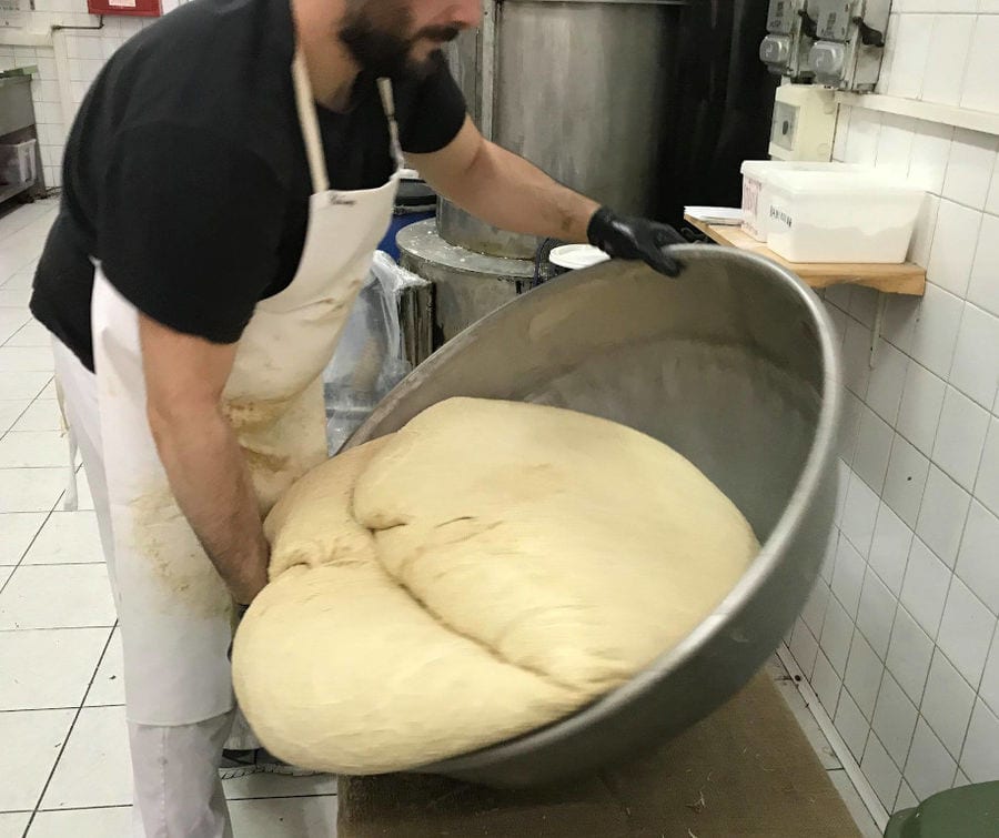 man with gloves mixing composition of Greek 'halva' in a basin at 'M. Kosmidis' workshop